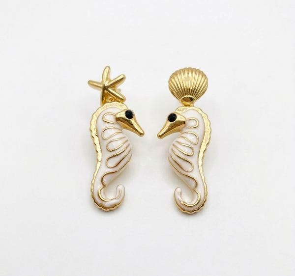 Pair of gold seahorse earrings on a white background