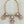 Load image into Gallery viewer, Necklace with pink and gold floral-like pendants on a dark surface
