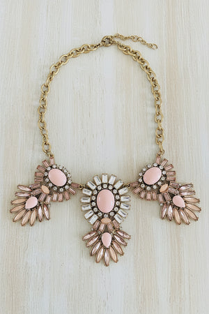 Necklace with pink and gold floral-like pendants on a dark surface