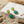 Load image into Gallery viewer, Pair of earrings with green gemstones on a white stone with beach elements.
