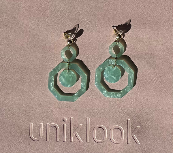 Pair of green earrings on a beige background with 'uniklook' branding.