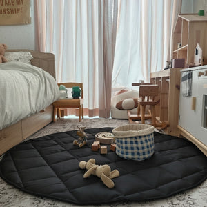 Children's room with a black play mat, toys, and furniture.