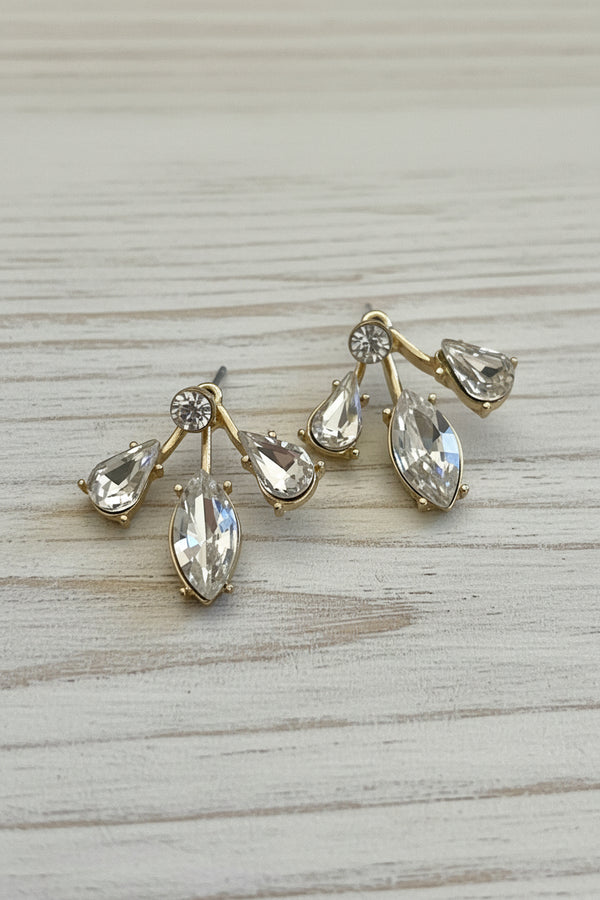 Gold earrings with clear gemstones on a light gray background