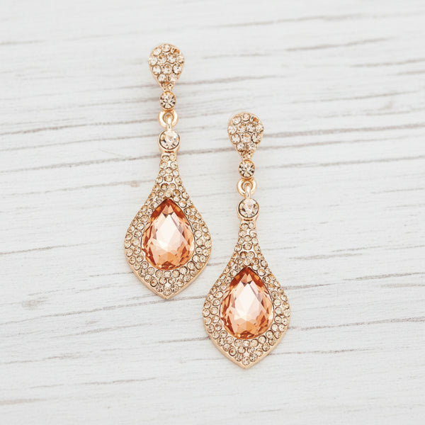 Rose gold earrings with orange teardrop-shaped gemstones on a white background