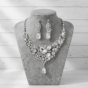 Silver jewelry set with necklace and earrings on a gray stone surface