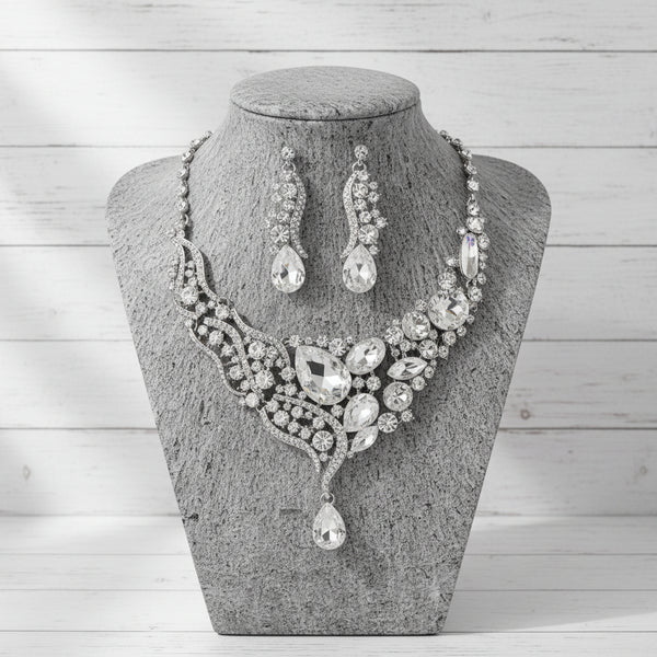 Silver jewelry set with necklace and earrings on a gray stone surface