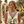 Load image into Gallery viewer, Woman in a white lace dress with jewelry and flowers, standing outdoors.
