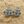 Load image into Gallery viewer, Anchor-shaped earrings with blue accents on a sandy surface
