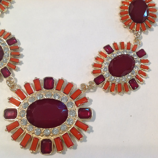 Ornate earrings with red and orange gemstones on a white background
