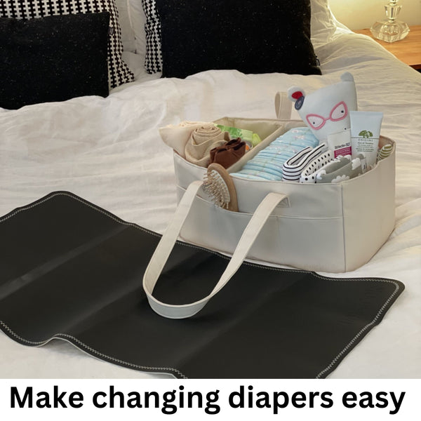 Baby changing mat with a bag containing diapers and wipes on a bed.