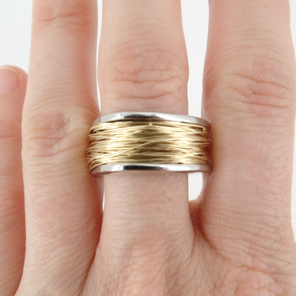 Gold and silver ring on a finger against a white background