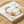 Load image into Gallery viewer, Gold bracelet with knot design on a marble surface with sand around
