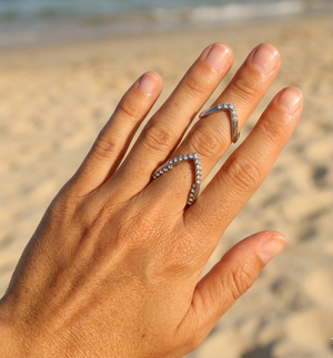Hand wearing two diamond rings on a beach