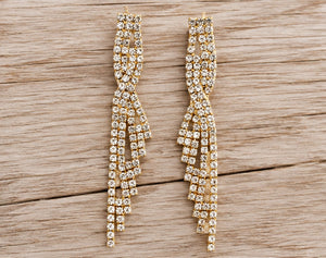 Golden cascading crystal earrings on pale barn wood