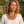 Load image into Gallery viewer, A woman with curly blonde hair wearing a multi-strand bohemian necklace with ornate gold-toned bars on a black cord, paired with matching dangling earrings and a white top, set against a soft-focus outdoor garden background.
