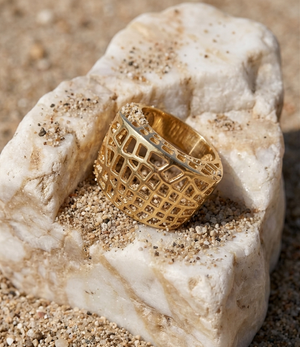 Gold ring with intricate design on a textured stone surface