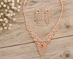 Peach crystal rose gold necklace and earrings on pale barn wood