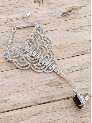 Silver crystal hand chain bracelet with black adjustable ring on pale rustic wood