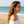 Load image into Gallery viewer, Woman wearing a white off-shoulder top and large earrings on a beach with ocean view
