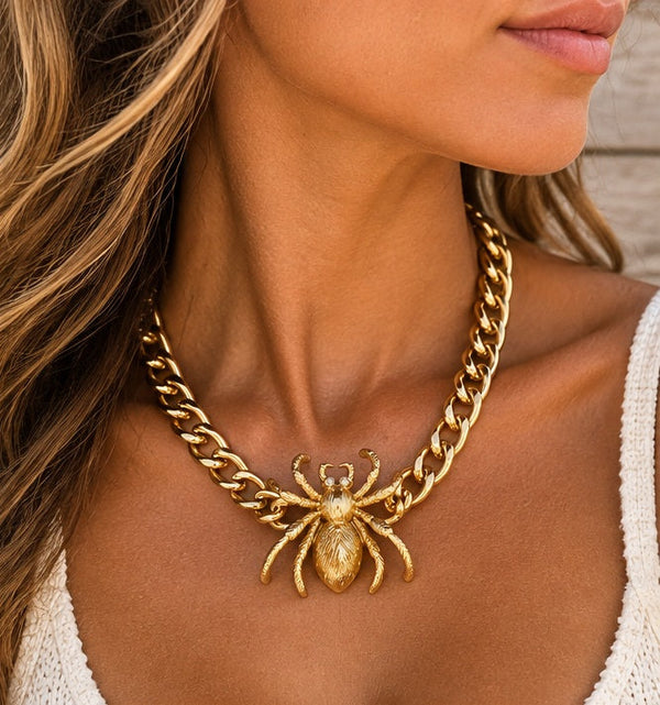 Gold spider necklace worn on a tanned model