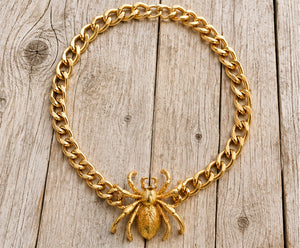 Gold spider necklace on pale barn wood