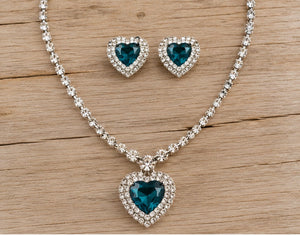 Teal heart necklace and clip-on earrings on pale barn wood