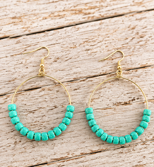 Turquoise beaded gold-tone hoop drop earrings on pale barn wood, 2.75 inches