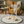 Load image into Gallery viewer, Dog lying on a round pet bed in a cozy living room with a yellow armchair and a lamp.
