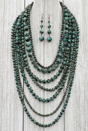 Long turquoise patina multi-strand necklace with matching earrings on display bust