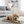 Load image into Gallery viewer, Dog lying on a quilted mat in a living room with a couch and lamp in the background.
