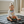 Load image into Gallery viewer, Child sitting on a black mat holding a colorful toy in a room with a crib and window.
