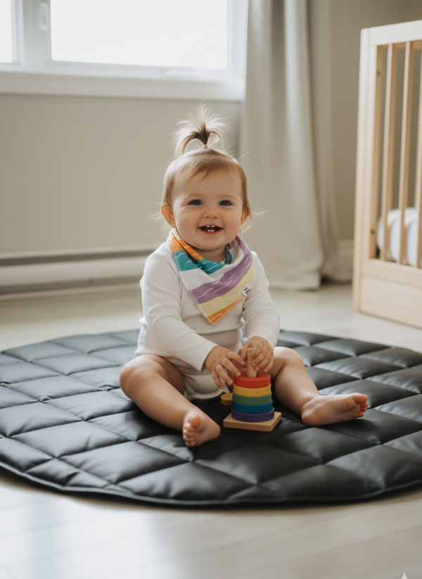 Child sitting on a black mat holding a colorful toy in a room with a crib and window.