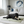 Load image into Gallery viewer, Dog lying on a rug in a living room with a couch and lamp in the background
