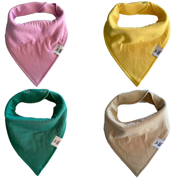 A set of four folded organic bibs in different colors: pink, yellow, green, and beige, each with a tag attached to the bottom corner.